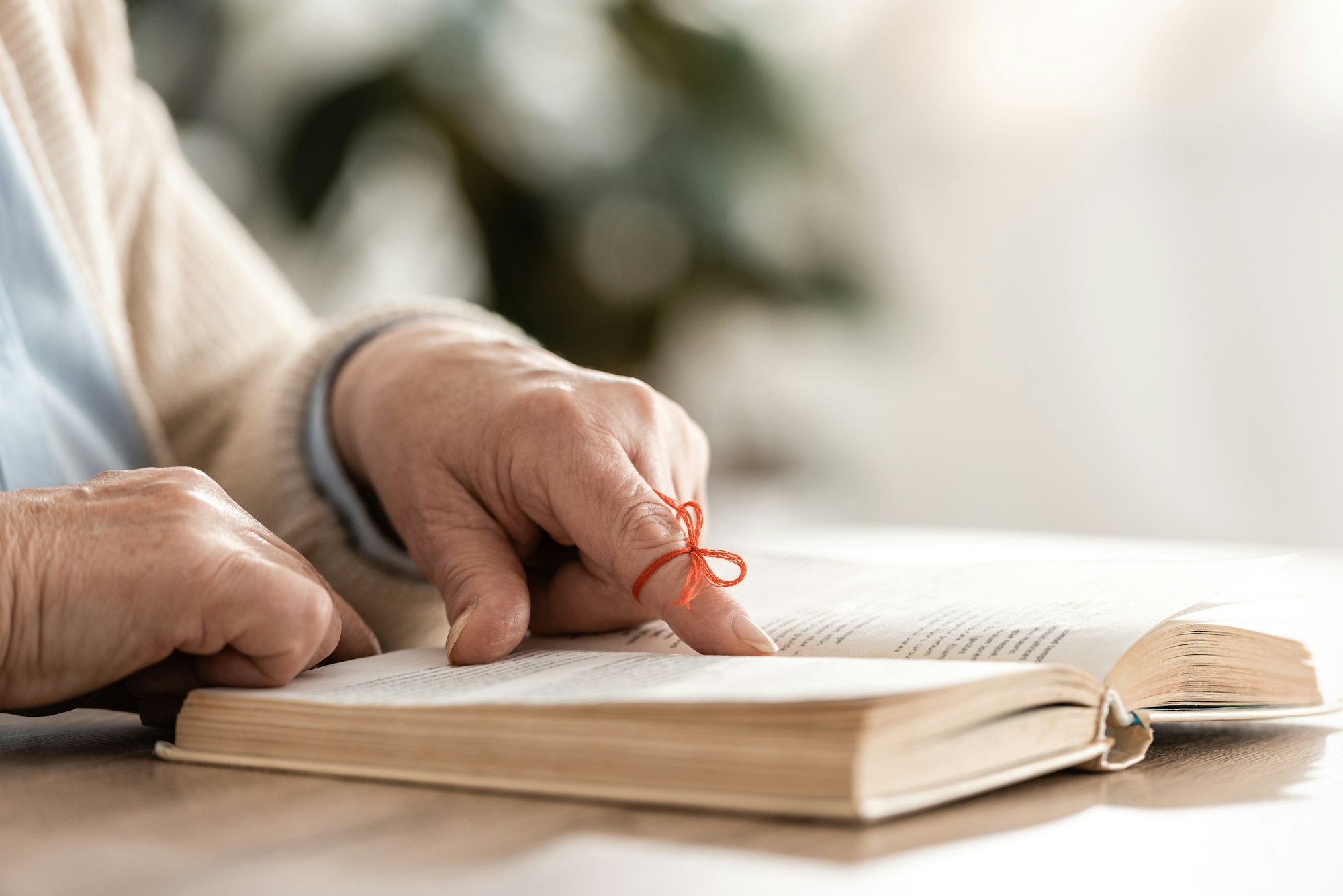 cropped view of senior woman with alzheimers disease string human finger reminder near book
