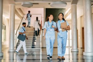 Happy female medical students walking through hallway at medical university.
